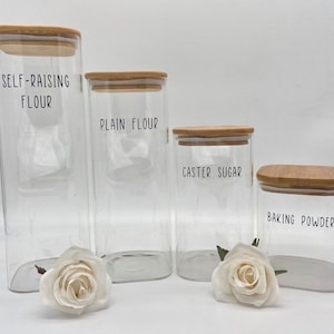 May include: Four glass jars with bamboo lids labelled "Self-Raising Flour", "Plain Flour", "Caster Sugar", and "Baking Powder".