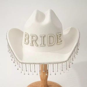 May include: A handmade wooden sign with the text "Welcome" in a playful font. The sign is painted white with a distressed finish, and features a decorative floral design in shades of pink and green. It measures approximately 12 inches wide.