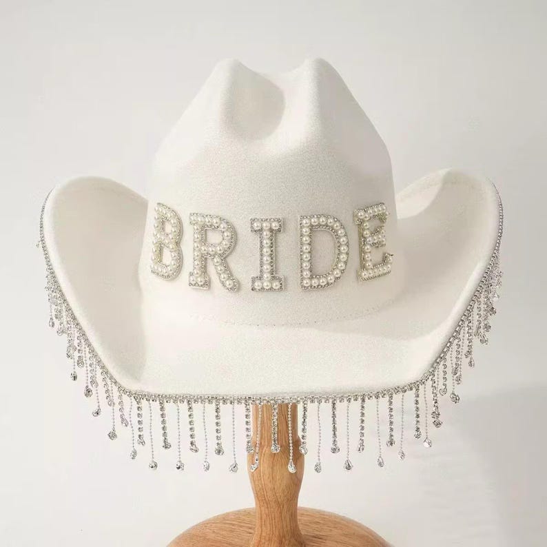 May include: A handmade wooden sign with the text "Welcome" in a playful font. The sign is painted white with a distressed finish, and features a decorative floral design in shades of pink and green. It measures approximately 12 inches wide.