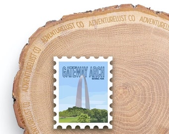 May include: A white postage stamp with a blue border and the text "GATEWAY ARCH NATIONAL PARK". The stamp features a blue and white illustration of the Gateway Arch in St. Louis, Missouri.