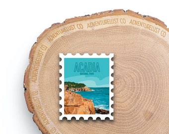 May include: A blue and white stamp with the text "Acadia National Park" and a scenic image of a rocky coastline with blue water.