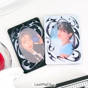 Puede incluir: Dos tarjetas fotogr&aacute;ficas rectangulares con im&aacute;genes de personas. Una tarjeta es negra con un borde decorativo blanco y negro, la otra es blanca con un borde similar. Las tarjetas tienen un acabado brillante. El texto "LostMaCity" es visible en la parte inferior.