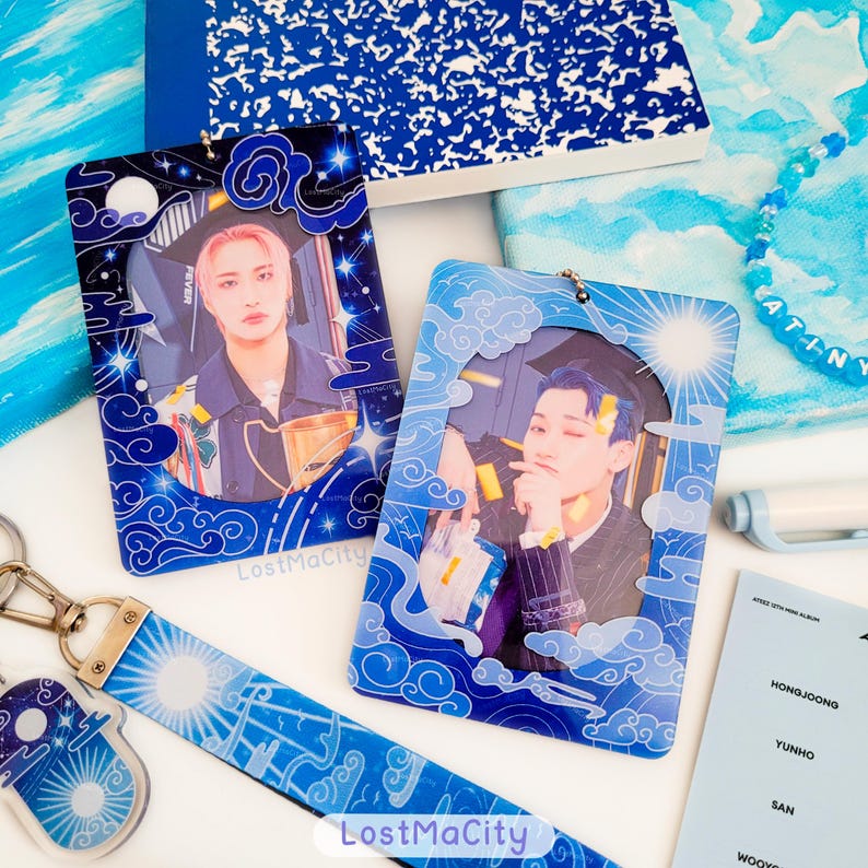 May include: Two blue acrylic photo card holders with images of people, framed by a cloud and star design. A matching lanyard and keychain are also visible, alongside a blue notebook and beaded bracelet. The text "LostMaCity" is printed on the items.