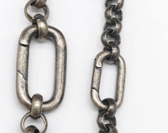 May include: Close-up of two antique silver-toned chains against a white background. The chains feature a combination of oval and circular links, with a textured, aged appearance. The chains are likely used for jewelry or accessories.