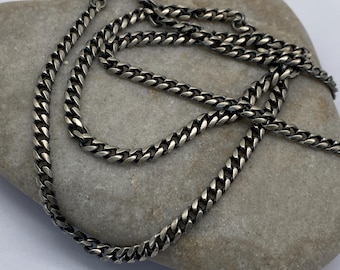 May include: A silver curb chain necklace with a lobster clasp. The chain is made of small, interlocking links.