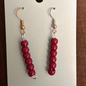 May include: A pair of earrings with maroon beads and gold hooks.