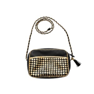 May include: A black rectangular crossbody bag featuring a gold and black woven checkerboard pattern on the front pocket. The bag includes gold piping, a long chain strap interwoven with black material, and a black tassel attached to the zipper.