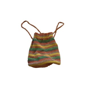 May include: A drawstring backpack made of crocheted yarn featuring horizontal stripes in shades of orange, yellow, green, and tan. The bag has a soft, flexible structure with two thin, matching crocheted straps attached to the top opening.