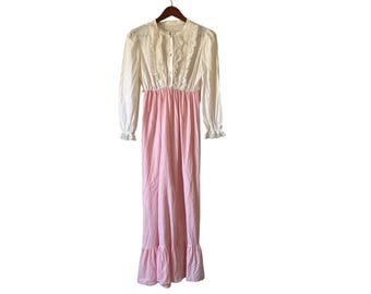 Könnte beinhalten: Ein Vintage-Nachthemd in Weiß und Rosa hängt an einem Holzkleiderbügel. Das Oberteil ist weiß mit langen Ärmeln und einem Rüschenkragen. Der untere Teil ist einfarbig rosa mit einem Rüschensaum. Das Nachthemd ist aus einem weichen, leichten Stoff gefertigt.