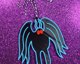 May include: Black and blue spider ornament with red eyes. The spider is hanging from a white and black string.
