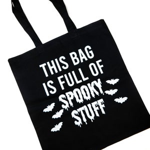 Peut inclure: Sac fourre-tout noir avec le texte blanc "THIS BAG IS FULL OF SPOOKY STUFF". Le sac présente des silhouettes de chauves-souris blanches et des poignées noires. Parfait pour Halloween ou pour transporter des objets effrayants.