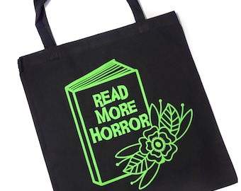 May include: Black tote bag with a green graphic of a book that says "Read More Horror" and a green flower with leaves.