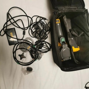 May include: A black carrying case with a yellow and green thermal imaging camera, a black power adapter, a black power cord, and other accessories.