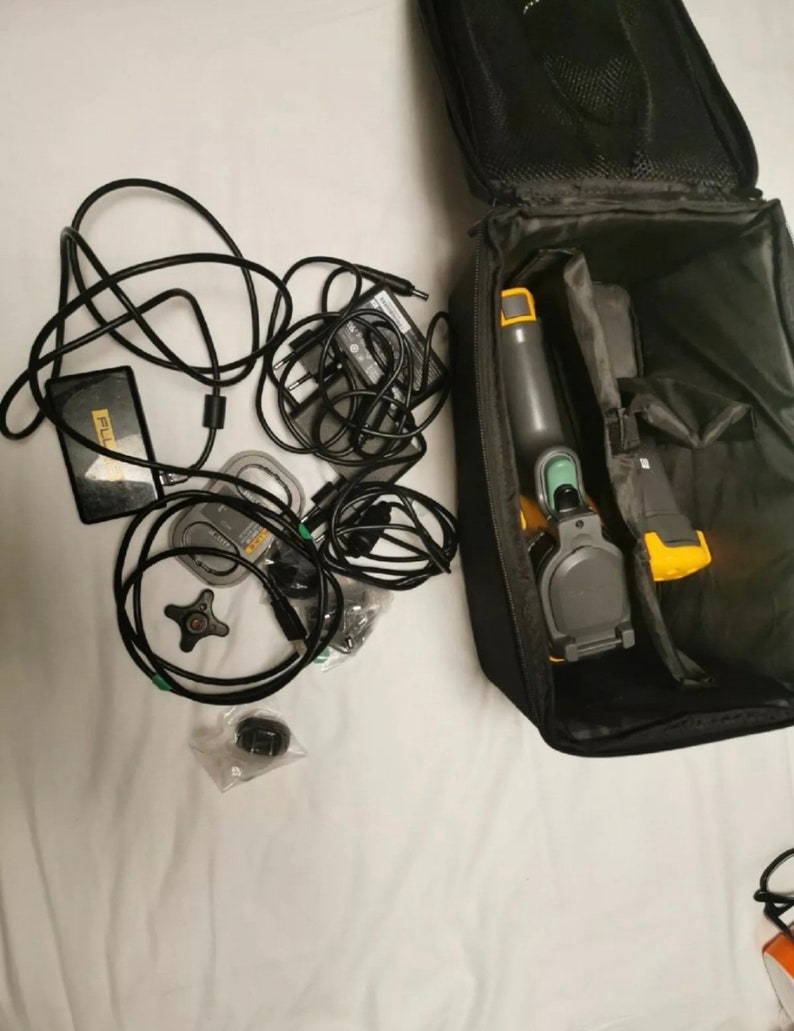 May include: A black carrying case with a yellow and green thermal imaging camera, a black power adapter, a black power cord, and other accessories.