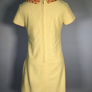 May include: A yellow short-sleeved dress with a large, embroidered, multi-colored collar.