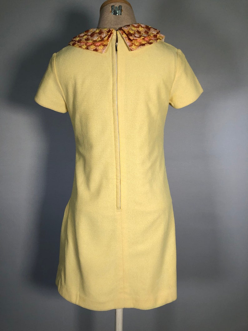 May include: A yellow short-sleeved dress with a large, embroidered, multi-colored collar.