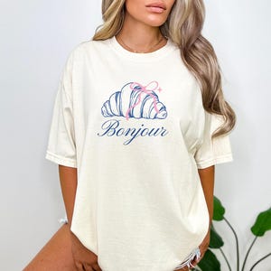 Bonjour Croissant Graphic Tee, Casual French Style Shirt, Women’s Light Beige Summer Top, Fashionable Streetwear T-Shirt