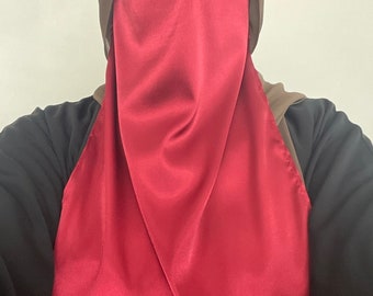 May include: A burgundy satin niqab with a brown hijab underneath.