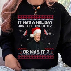 Op de afbeelding: Zwarte kersttrui met een rood en wit sneeuwvlokkenpatroon. Het toont een man met een kerstmanmuts en een zwart shirt met de tekst "Het was een feestdag zoals alle andere... of toch niet?"