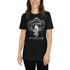 Peut inclure: T-shirt noir avec un motif blanc représentant une rose, un serpent et des ailes. Le texte "LA FEMME" est écrit au-dessus du motif.