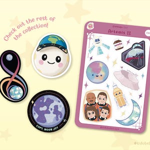 May include: A collection of stickers and sticker sheets with a space theme. The stickers include a smiling moon wearing a hat with the Earth on it, a planet, and a sticker sheet with various space-themed illustrations. Text includes "Artemis II".