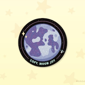 May include: A round sticker featuring a stylized moon with a textured, purple surface. The moon is set against a light blue background within a black border with stars. The text "COPY, MOON JOY" is at the bottom.