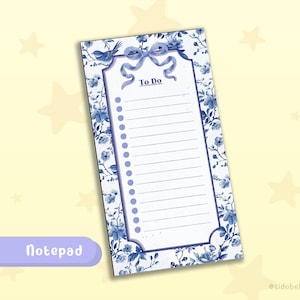 May include: A rectangular notepad with a floral design in shades of blue. The notepad features a "To Do" list format with a decorative bow and bird illustration at the top. The word "Notepad" is written in a purple rectangle at the bottom.