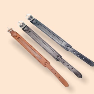 May include: Three leather dog collars in brown, black and dark grey with silver buckles.