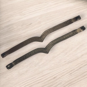 May include: Two dark green leather bracelets with a decorative stitching pattern and metal clasps.