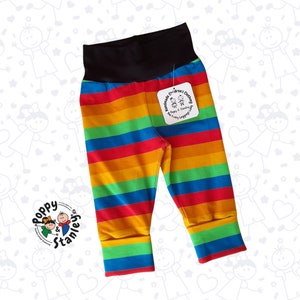 May include: Rainbow striped leggings for children with a black waistband. The leggings have a tag that says "Handmade Children's Clothing Poppy & Stanley The Funky Leggings Lady".