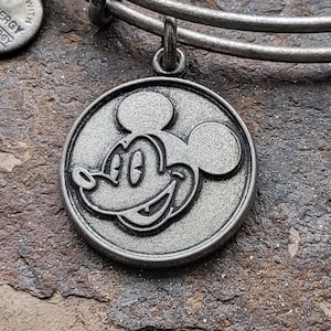 Könnte beinhalten: Silbernes Charm-Armband mit einem silbernen Mickey Mouse-Anhänger. Der Anhänger zeigt ein detailliertes Profil von Mickey Mouse's Gesicht.