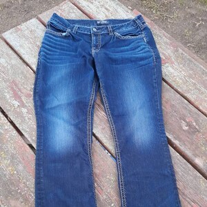 May include: A pair of dark blue denim jeans with white stitching. The jeans have a straight leg fit and a classic five-pocket style.