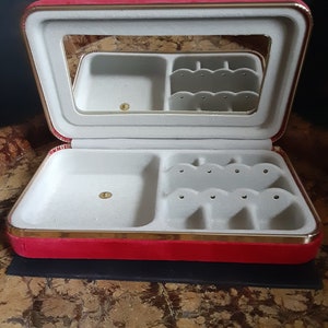 May include: Red velvet jewelry box with a gold trim and a mirror inside. The box has compartments for rings and earrings.