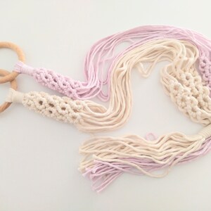 Peut inclure: Un porte-plante en macramé avec deux anneaux en bois et un dégradé de couleur rose et crème. Le porte-plante a de longues franges et est fait de cordon de coton.