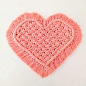 May include: A pink crocheted heart-shaped coaster with a fringe border.
