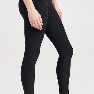 Pode incluir: Uma mulher vestindo leggings pretos e tênis de corrida brancos com detalhes em rosa. Os tênis têm uma sola grossa e acolchoada.
