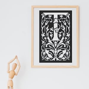 Könnte beinhalten: Ein schwarz-weißer gerahmter Druck eines dekorativen Buchstabens "I" mit einem floralen Design. Der Buchstabe ist weiß und das florale Design ist schwarz.
