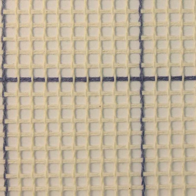 May include: Close-up of white Aida cloth with blue cross-stitch threads. The cloth is woven in a grid pattern, creating a surface for embroidery.