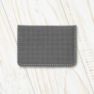 Op de afbeelding: Een grijze, rechthoekige, getextureerde kaarthouder met een rasterpatroon. De kaarthouder is gemaakt van een zacht, flexibel materiaal.