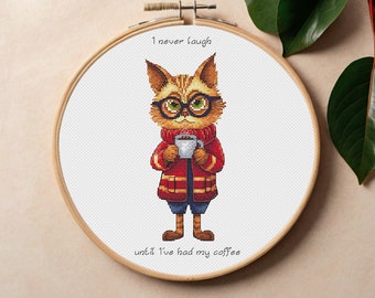 Puede incluir: Un patrón de punto de cruz con un gato de dibujos animados que lleva gafas y un abrigo rojo, sosteniendo una taza de café. El texto dice "Nunca me río hasta que no he tomado mi café."