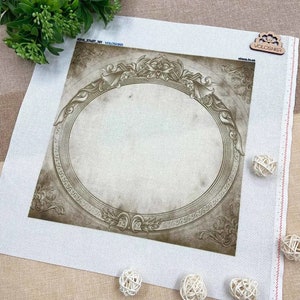 Op de afbeelding: Een canvas met een ovaal frame in sepia-tinten. Het frame heeft sierlijke bloemen- en krulwerkdetails. Het canvas is wit met een decoratieve rand en de tekst "VOLOSHKA" is zichtbaar.