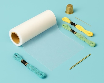 May include: A roll of white mesh fabric, two spools of yellow embroidery floss, one spool of green embroidery floss, a gold thimble, and two gold needles on a light blue background.