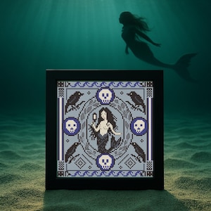 Puede incluir: Un bordado de punto de cruz enmarcado con un diseño de sirena con calaveras y cuervos en una combinación de colores azul y gris. La sirena sostiene un espejo. El fondo muestra una silueta de una sirena nadando bajo el agua.
