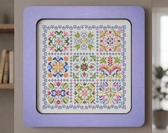Può includere: Un campionario a punto croce incorniciato in una cornice di legno color lavanda. Il campionario presenta nove colorati disegni floreali in un motivo a griglia, con un bordo decorativo. Il ricamo utilizza rosa, blu, giallo e verde. La cornice misura circa 25 cm.