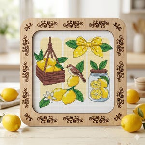 Peut inclure: Un cadre en bois carré avec des coins ornés de volutes contenant une broderie au point de croix. Le motif présente un panier suspendu marron rempli de citrons, un petit oiseau posé sur un citron, un nœud jaune à pois et un bocal en verre de citrons.