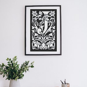 Könnte beinhalten: Schwarz-weiß gerahmter Druck eines dekorativen Buchstabens "J" mit floralen Designs.