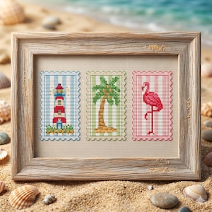 May include: A framed cross-stitch embroidery featuring three rectangular postage stamp designs. The left shows a red and white lighthouse, the center a green palm tree, and the right a pink flamingo, all set against a light beige fabric background.