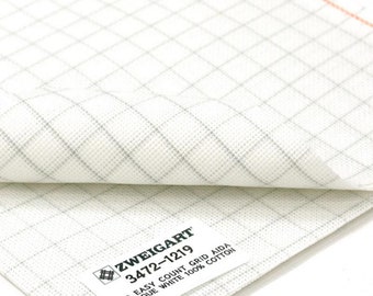 May include: White Aida fabric with a grid pattern. The fabric is folded over to show the label, which reads "ZWEIGART 3472-1219 20ct Easy Count Grid Aida - Antique White 100% Cotton".