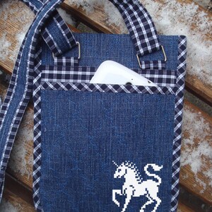 May include: A blue denim crossbody bag with a white and black checked trim. The bag has a white embroidered unicorn design and a pocket for a phone.