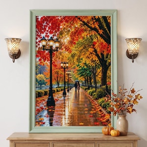 May include: A framed wall art print depicting a rain-slicked park path lined with black street lamps and vibrant autumn trees in shades of red, orange, and yellow. Two figures walk under an umbrella along the reflective, leaf-covered walkway.